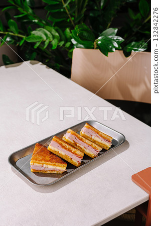 Delicious layered sandwich served on a tray in a modern cafe setting 132842276
