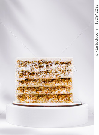 Delicious multi-layered cake on a white pedestal with a smooth backdrop 132842282