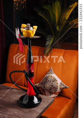 Unique hookah setup with fruit and decorative cushion in cozy lounge Unique hookah setup with fruit and decorative cushion in cozy lounge 132842333