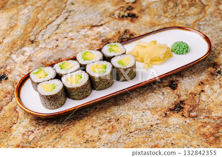 Fresh sushi rolls served with ginger and wasabi on a marble table Fresh sushi rolls served with ginger and wasabi on a marble table 132842355