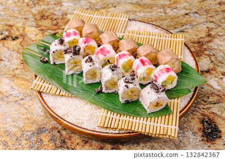 Unique sushi platter featuring colorful rolls with fruits and toppings 132842367