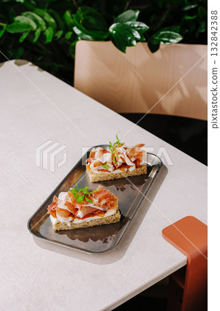 Delicious open-faced sandwiches served on a modern table with greenery 132842388