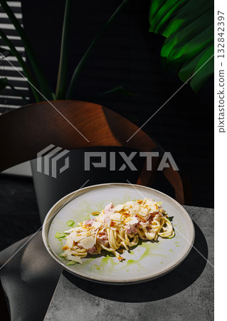 Pasta dish served on a ceramic plate in a minimalist dining setup Pasta dish served on a ceramic plate in a minimalist dining setup 132842397