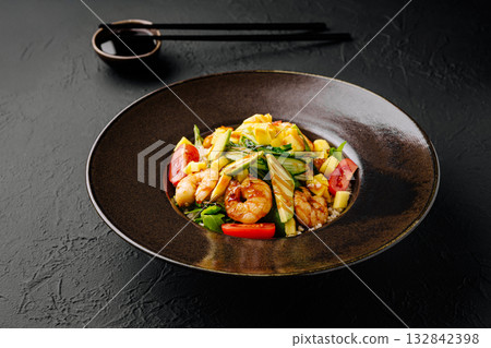 Shrimp stir-fry with vegetables served in a dark bowl on a textured surface Shrimp stir-fry with vegetables served in a dark bowl on a textured surface 132842398