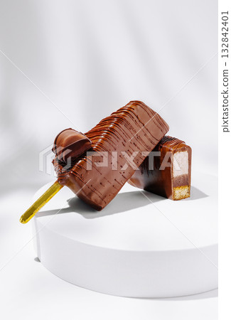 Delicious chocolate popsicle and cut piece on a white display Delicious chocolate popsicle and cut piece on a white display 132842401