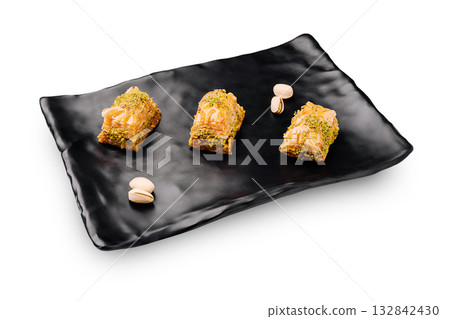 Delicious baklava served on a stylish black plate with pistachios Delicious baklava served on a stylish black plate with pistachios 132842430