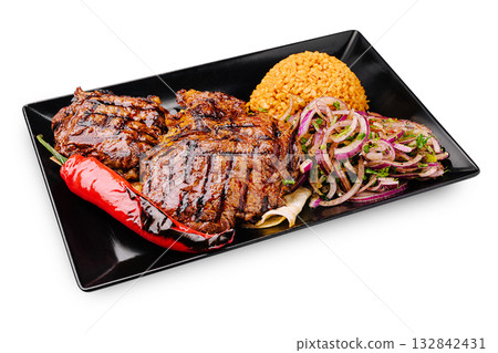 Sizzling grilled meat with rice and vegetables served on a black plate Sizzling grilled meat with rice and vegetables served on a black plate 132842431