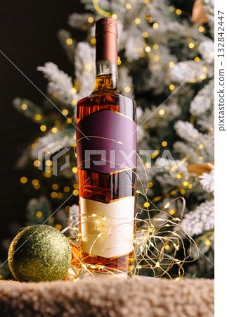 Festive whiskey bottle surrounded by Christmas decorations and lights 132842447