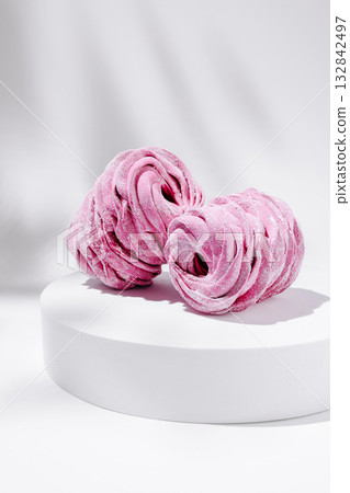 Delicate pink pastries arranged artistically on a white pedestal Delicate pink pastries arranged artistically on a white pedestal 132842497