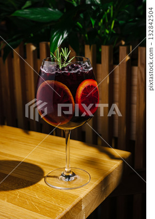 Refreshing blood orange drink served in a tall glass with rosemary garnish 132842504