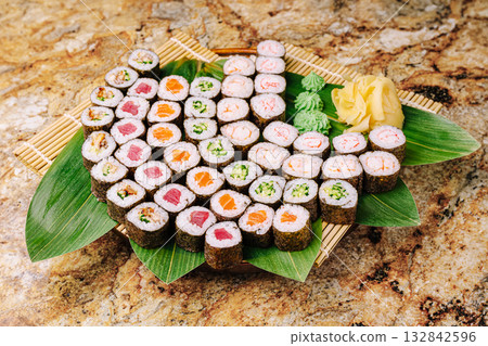 Delicious variety of sushi on a bamboo platter with fresh garnishes 132842596