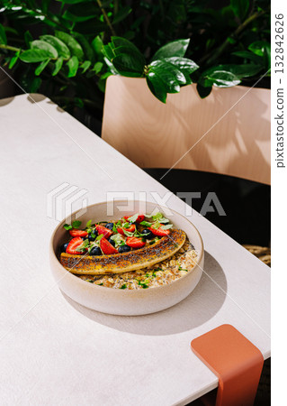 Enjoying a healthy bowl of oatmeal topped with fresh fruit in a sunny cafe 132842626