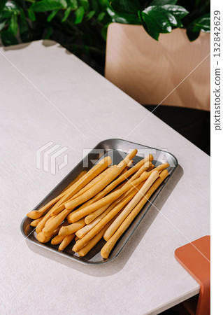 Crispy breadsticks served on a metal tray in a cozy dining area Crispy breadsticks served on a metal tray in a cozy dining area 132842629