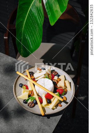 Delicious cheese platter served with fresh fruits and nuts on a table 132842635