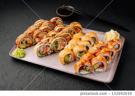 Colorful sushi platter with various rolls and garnishes on a dark surface 132842638