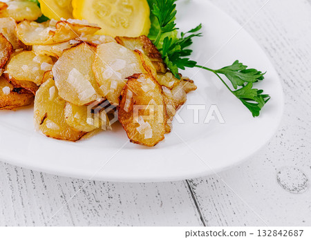 Delicious roasted potatoes with greens and zucchini slices on white plate 132842687