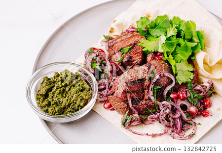 Delicious grilled meat served with fresh herbs and chutney on flatbread Delicious grilled meat served with fresh herbs and chutney on flatbread 132842725