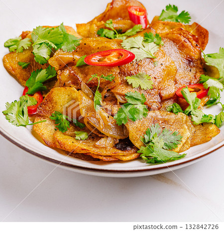 Crispy fried potato dish garnished with fresh herbs and chilies Crispy fried potato dish garnished with fresh herbs and chilies 132842726