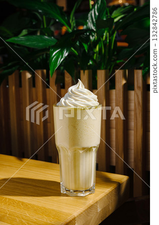 Delicious milkshake topped with whipped cream in a cozy cafe setting Delicious milkshake topped with whipped cream in a cozy cafe setting 132842786