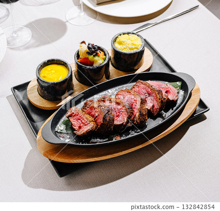 Delicious steak served on a sizzling platter with side dishes at restaurant 132842854