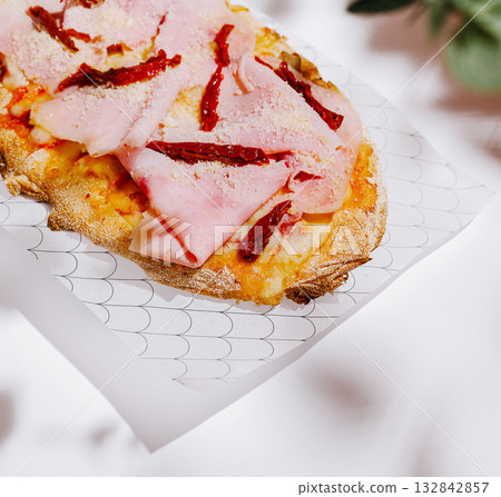 Delicious flatbread topped with ham and sun-dried tomatoes on a plate Delicious flatbread topped with ham and sun-dried tomatoes on a plate 132842857