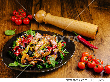 Colorful vegetable stir-fry served on a black plate with fresh ingredients 132842860