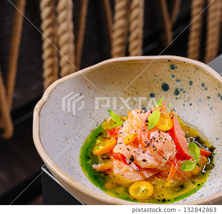 Elegant salmon dish with vibrant garnishes served in a unique bowl 132842863