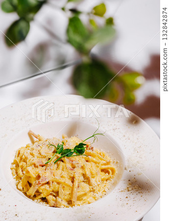 Creamy pasta dish with herbs served in stylish restaurant setting 132842874