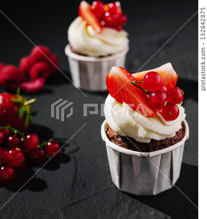 Delicious chocolate cupcakes topped with fresh berries and cream Delicious chocolate cupcakes topped with fresh berries and cream 132842875