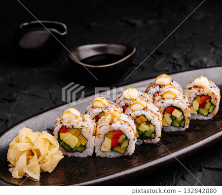 Fresh sushi rolls served with ginger and sauce on a black plate Fresh sushi rolls served with ginger and sauce on a black plate 132842880