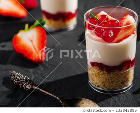 Delicious layers of creamy dessert with fresh berries on dark stone surface 132842889