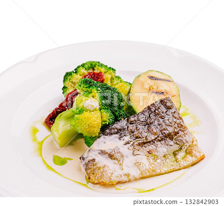 Delicious grilled fish served with fresh vegetables garnished with sauce 132842903