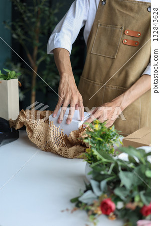 A small business owner, a florist or a gift shop worker preparing a customer's order. A small business owner, a florist or a gift shop worker preparing a customer's order. 132843628