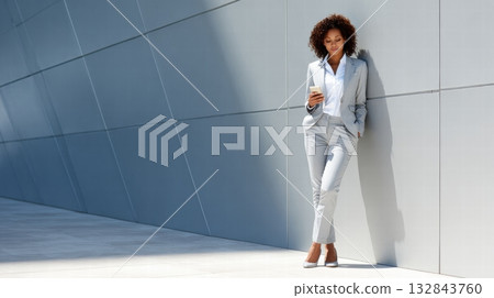 corporate woman in a suit is smiling and holding a phone 132843760