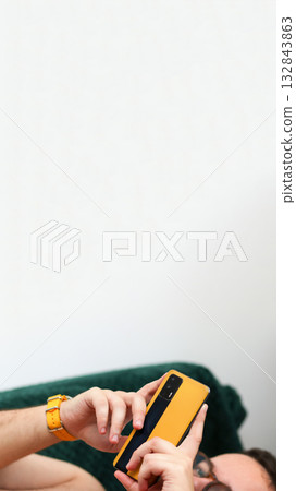 vertical shot capturing a man engaged in active smartphone use. online shopping or reviewing an important message on phone. Vertical banner for reel or stories vertical shot capturing a man engaged in active smartphone use. online shopping or reviewing an important message on phone. Vertical banner for reel or stories 132843863
