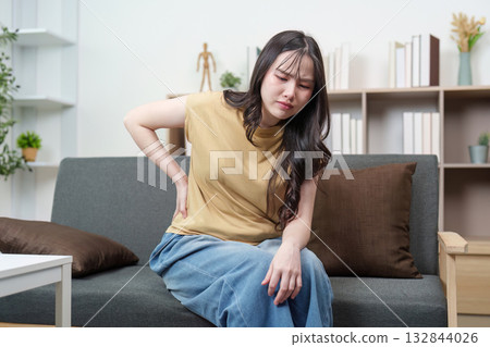 Health Awareness: Young woman experiencing back pain at home 132844026