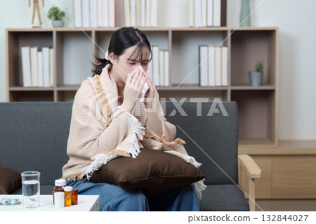 Health and Wellness. Young woman feeling emotional distress at home, blowing her nose. Health and Wellness. Young woman feeling emotional distress at home, blowing her nose. 132844027