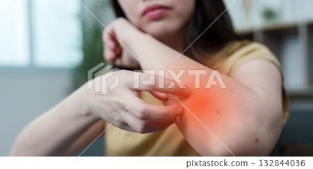Health Awareness: Young woman experiencing arm pain at home Health Awareness: Young woman experiencing arm pain at home 132844036