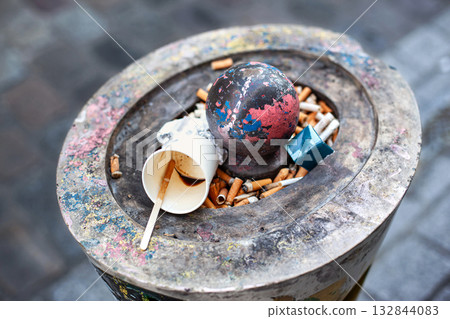 Cigarette butts and other waste in an ashtray 132844083