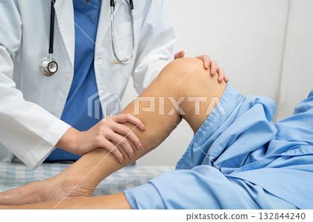 Doctor checking Asian elderly woman patient with scar knee replacement surgery in hospital. 132844240