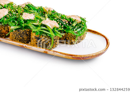 Delicious sushi rolls topped with vibrant green seaweed salad for lunch Delicious sushi rolls topped with vibrant green seaweed salad for lunch 132844259