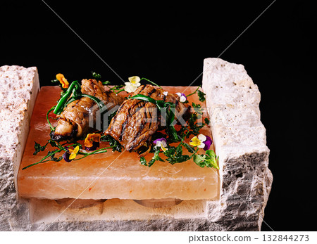 Gourmet beef rolls served on Himalayan salt block with edible flowers 132844273