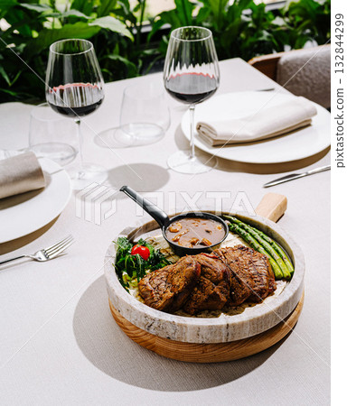 Delicious beef dish served with vegetables and sauce in elegant dining setting Delicious beef dish served with vegetables and sauce in elegant dining setting 132844299