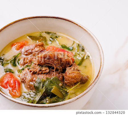 Savory beef stew with fresh herbs and vegetables in a rustic bowl Savory beef stew with fresh herbs and vegetables in a rustic bowl 132844320