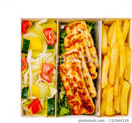 Grilled chicken and fresh salad served with crispy fries in a takeout container 132844326