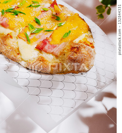 Tasty flatbread topped with cheese and ham served in a cozy setting Tasty flatbread topped with cheese and ham served in a cozy setting 132844331