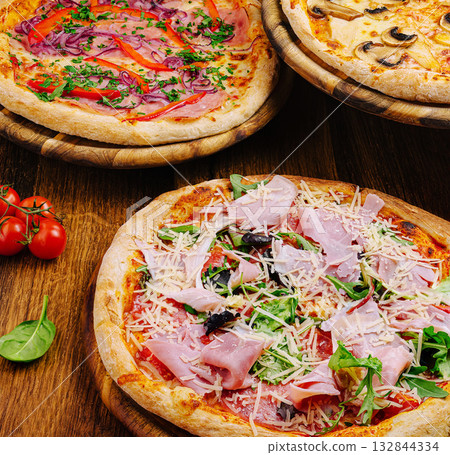 Delicious pizzas served on wooden plates at a cozy restaurant Delicious pizzas served on wooden plates at a cozy restaurant 132844334