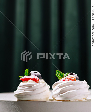 Sweet meringue desserts topped with fresh berries and mint leaves Sweet meringue desserts topped with fresh berries and mint leaves 132844340