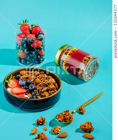 Fresh fruit and granola create a colorful breakfast setup on a blue background 132844377