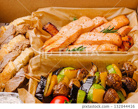 Fresh grilled salmon and vegetable skewers served in a takeout box 132844416